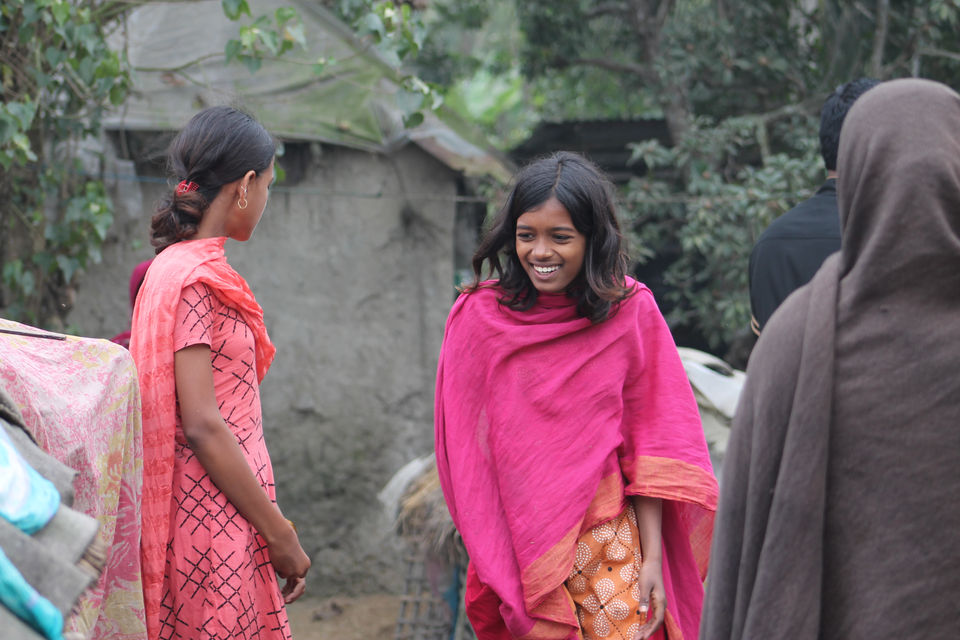 Zwei lächelnde Mädchen sprechen sich, tragen farbenfrohe Kleidung, DWF PROJEKT KHULNA, BD, im Freien.