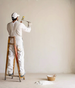 painter painting the wall wearing white overalls facing the wall.jpg
