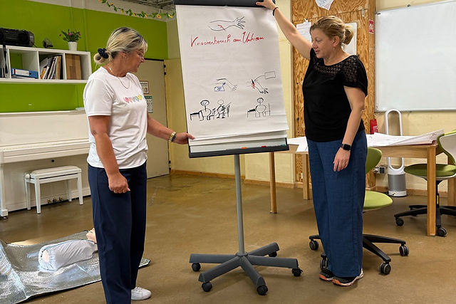 Zwei Frauen präsentieren am Flipchart die wichtigsten Schritte bei der Ersten Hilfe im Projekt Schule & Beruf Berlin e.V.