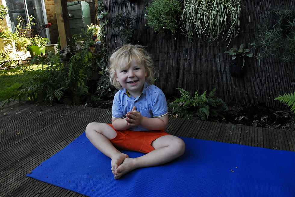 Close-up view of a child’s feet in a seated yoga pose on a wooden floor