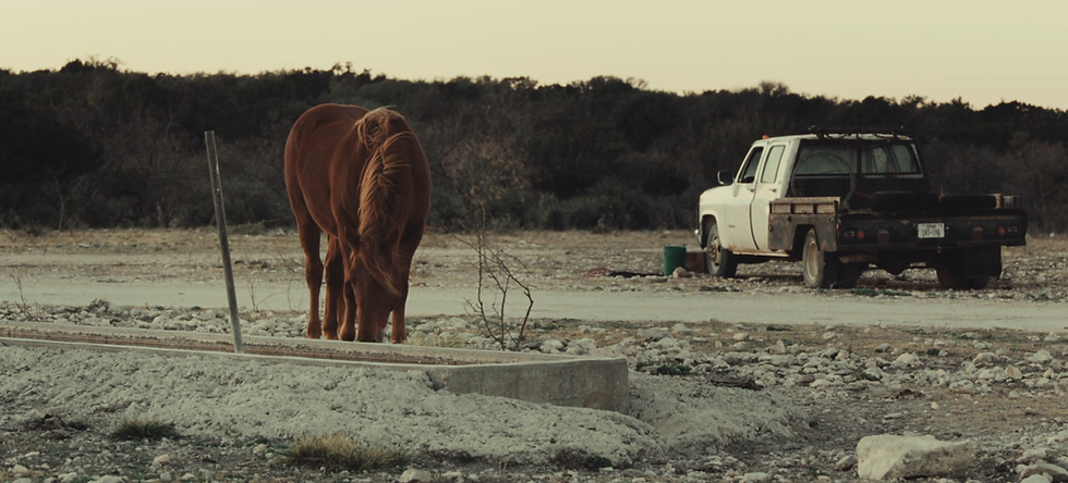 Exterior set design of a deserted landscape with a horse and a pickup truck in low-income rural Texas for a modern-day film.