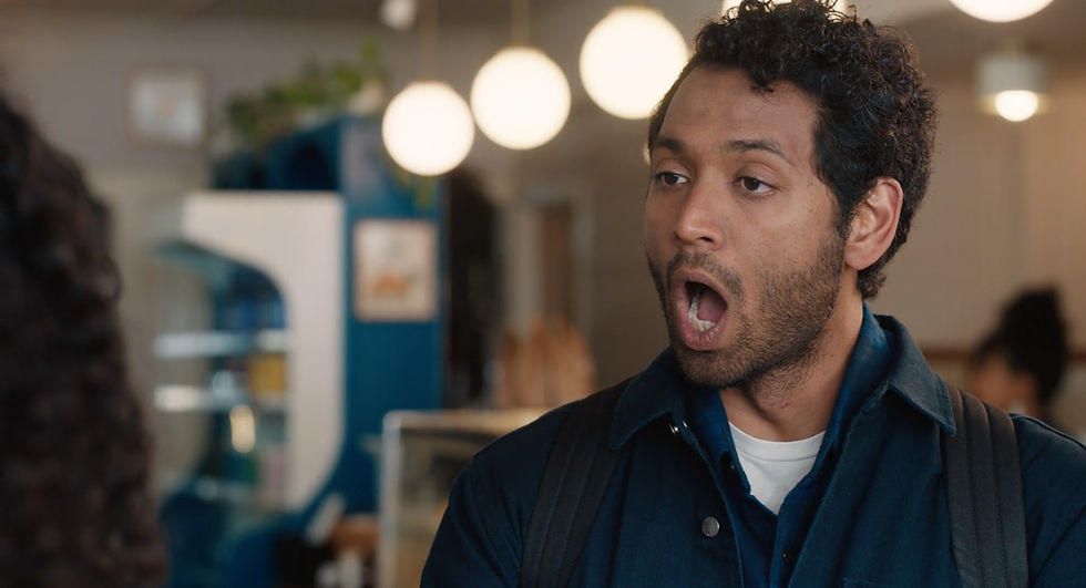 An actor in a modern coffee shop set designed for a present-day comedy movie by NY Production Designer Kelsey Hannah Walsh.