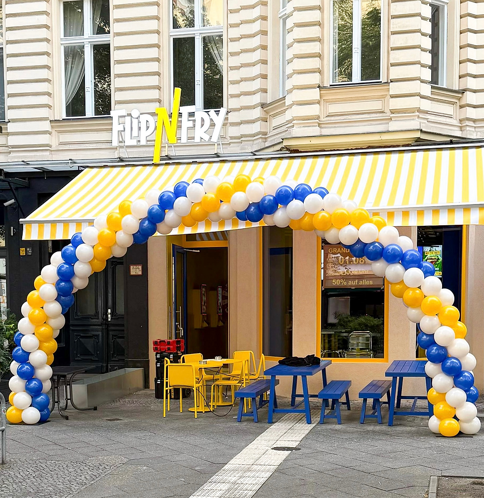 Ballonbogen in Blau, Gelb und Weiß am Eingang eines Restaurants