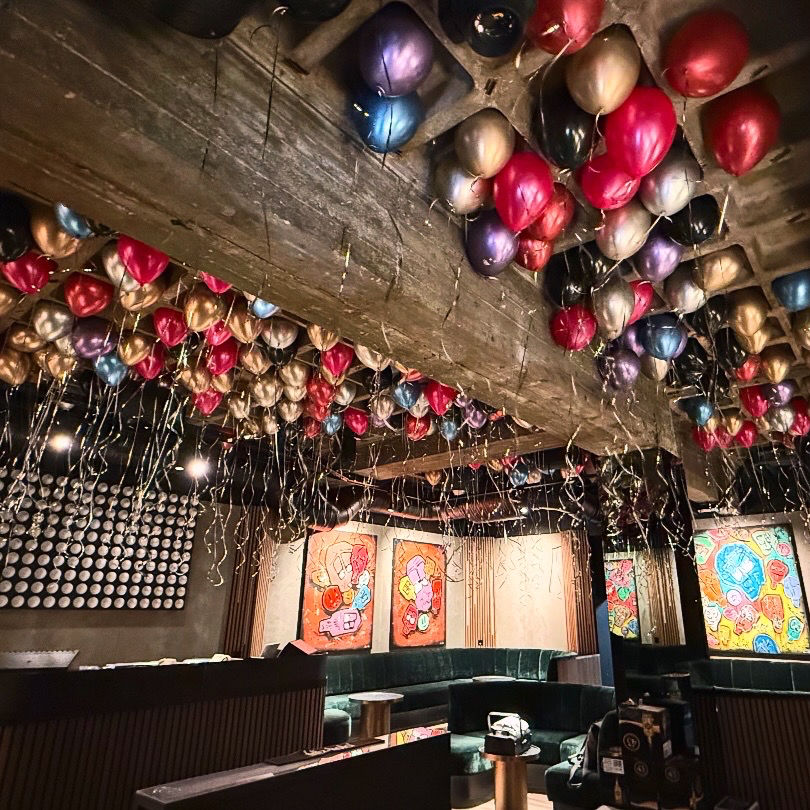 Metallic-Ballondekoration an der Decke in Rot, Violett, Gold und Schwarz