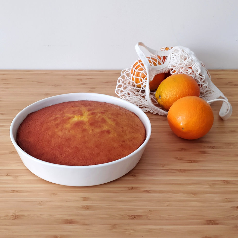 תבנית קרמיקה עגולה לאפיית עוגה, עם עוגה אפויה ומקומחת בתוכה, מונחת על משטח עץ ליד רשת בד עם תפוזים.