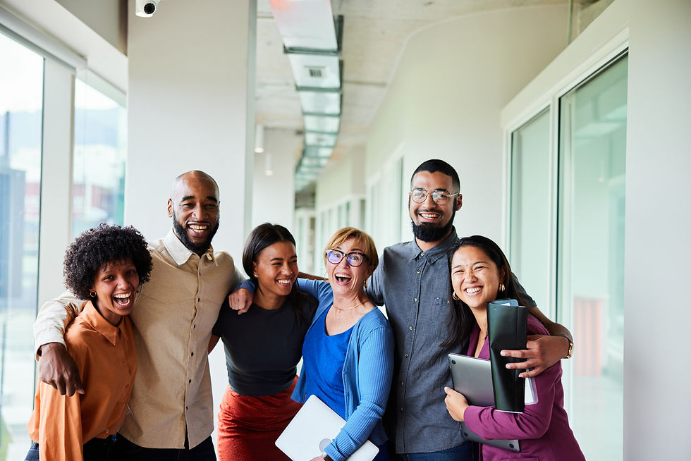 Laughing businesspeople standing arm in arm in an office hallway