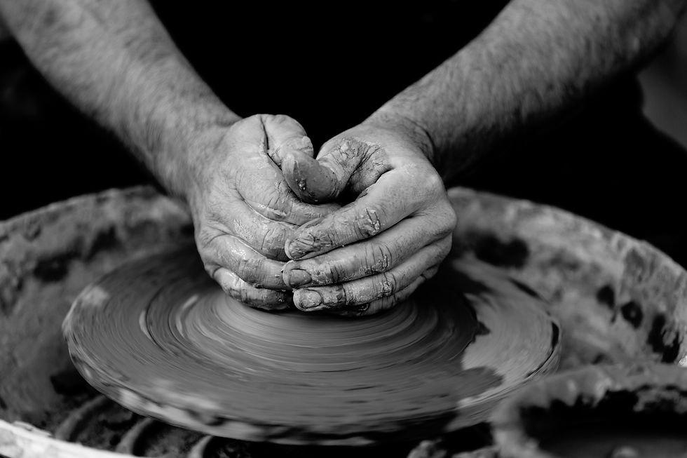Black and white photo of hands spinning pottery