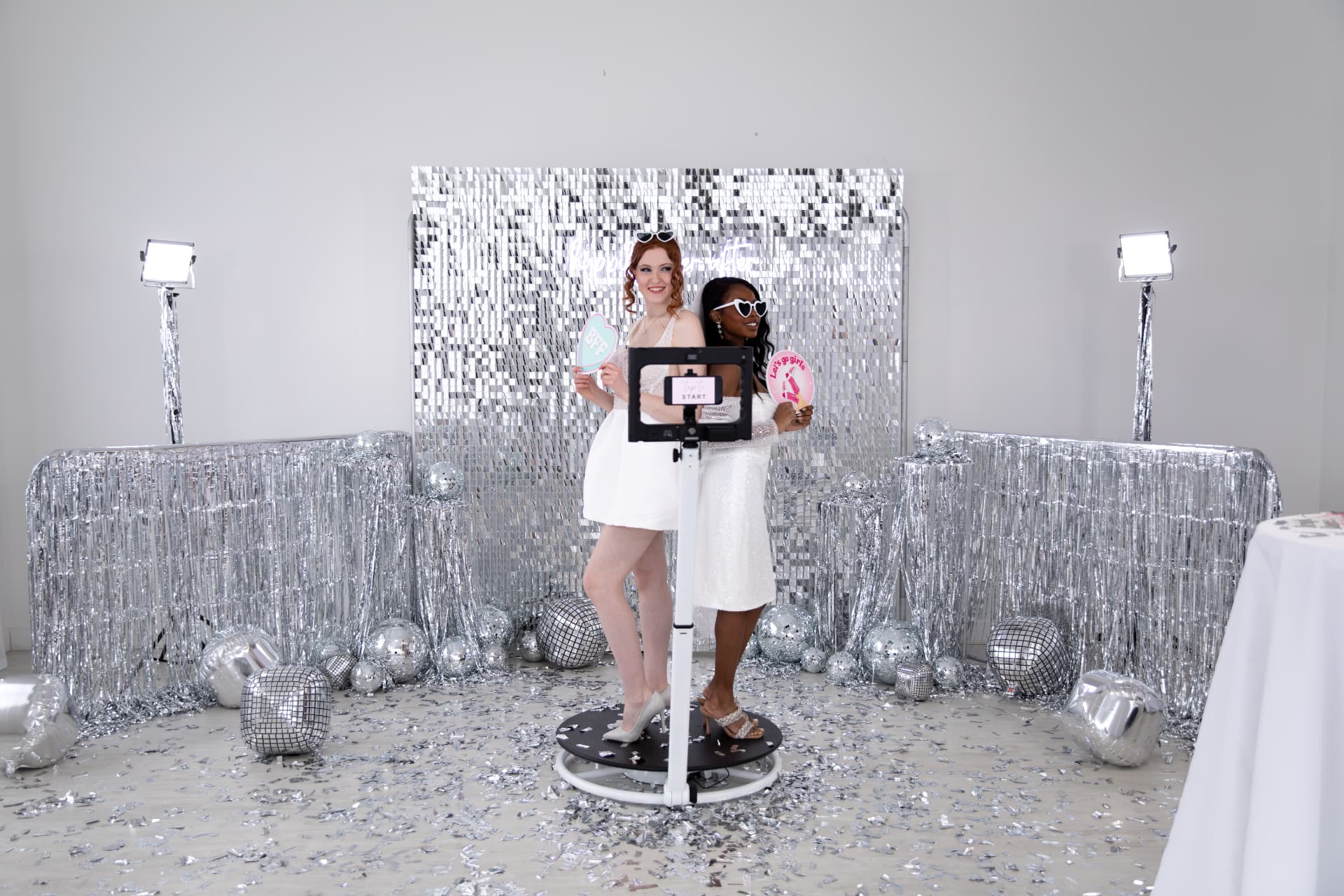 Two guests posing on the 360 video booth at a party