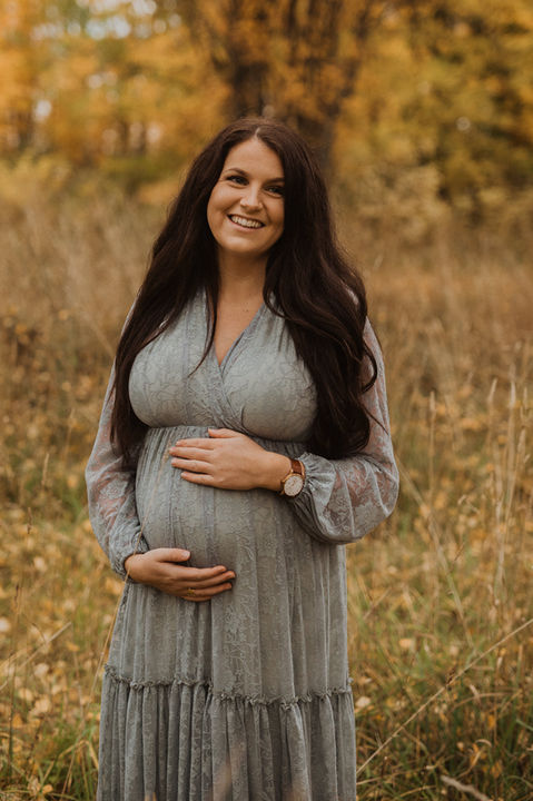 Gravid kvinna håller om sin mage och har på sig en gravidklänning