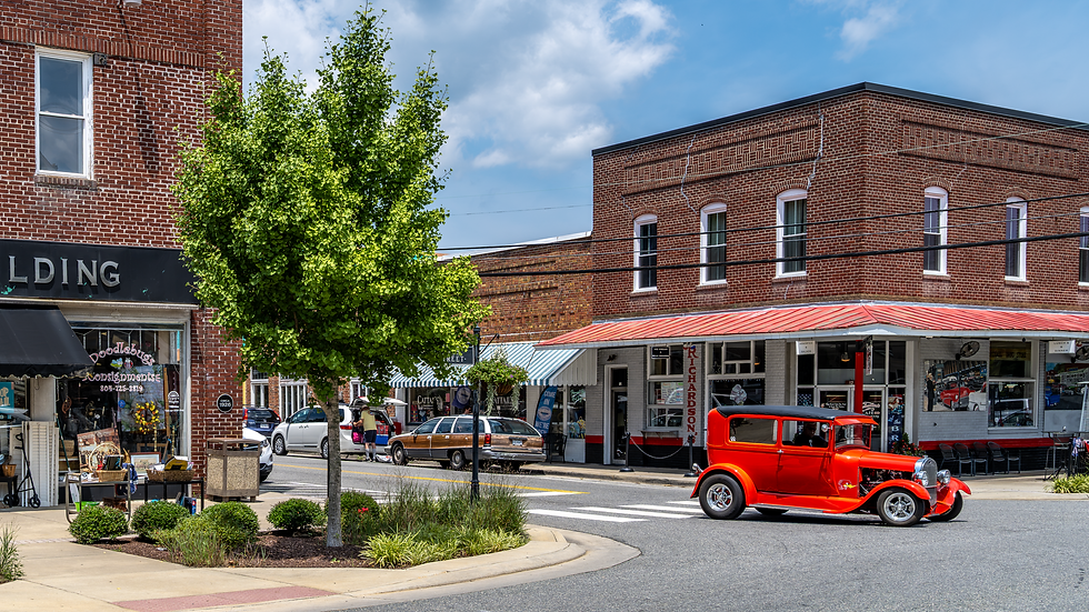 Red classic car driving in front of brick buildings