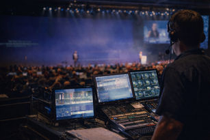 Live event AV technician monitoring video, audio, and show cues from the control position during a corporate conference