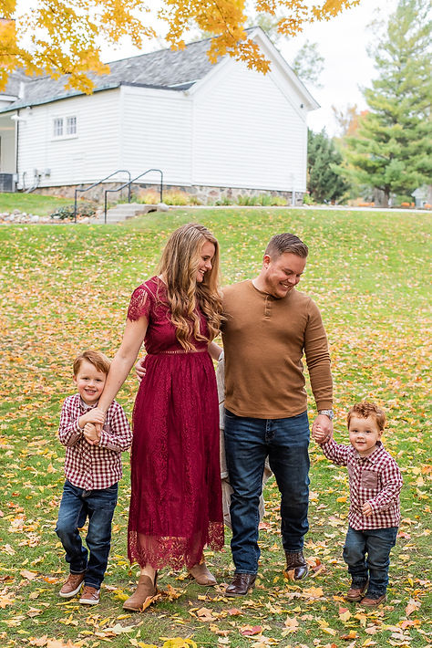 A family of four walking in a fall leaf field.