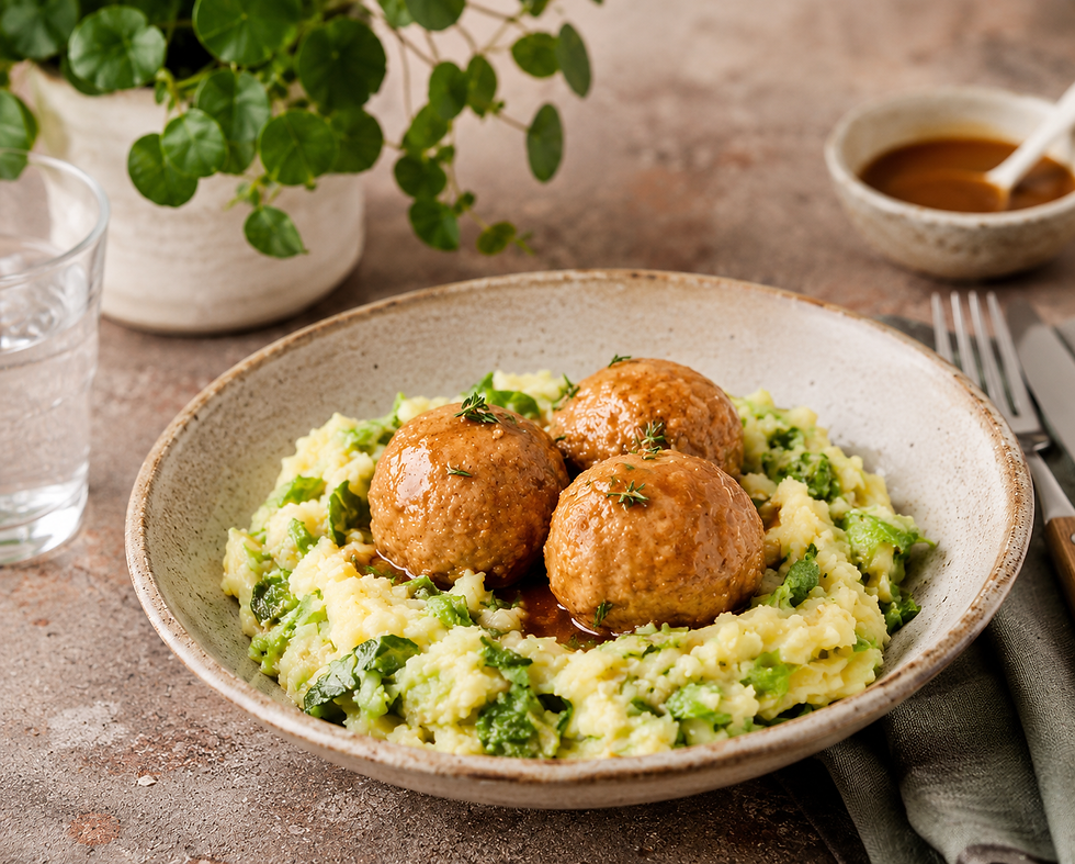 Photo culinaire gourmande de boulettes de viande nappées de sauce, servies avec une purée d’endives crémeuse dans une assiette en grès beige sur un plan de travail rustique, avec une plante verte en arrière-plan et une ambiance chaleureuse.