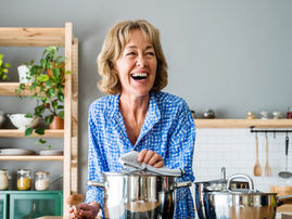 femme 50 ans qui sourit en faisant à manger