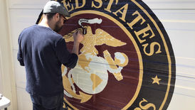 Mike Sekletar painting a United States Marines emblem mural on a wall.