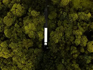 Aus der Vogelperspektive: Ein E-Lkw fährt durch einen grünen Wald