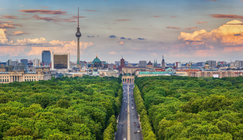 Das Brandenburger Tor im Zentrum, davor die Straße des 17. Juni und der Tiergarten. Im Hintergrund der Fernsehturm