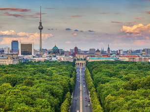 Das Brandenburger Tor im Zentrum, davor die Straße des 17. Juni und der Tiergarten. Im Hintergrund der Fernsehturm