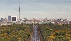 Berlin mit Fernsehturm und Brandenburger Tor, die Straße des 17. Juni mit vielen E-Autos darauf.