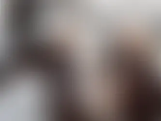 Ein Mann und eine Frau lachen vor einem E-Auto, das gerade lädt, in die Kamera