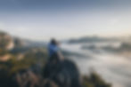 Man sitting on mountain top taking photo