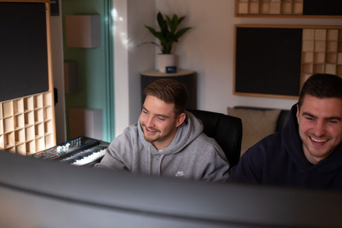 Zwei Produzenten lachen im Tonstudio.