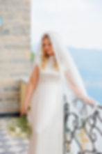 Bride in white dress holding bouquet, wearing Mist bridal veil, looking down. Anna Lindh's bridal collection.