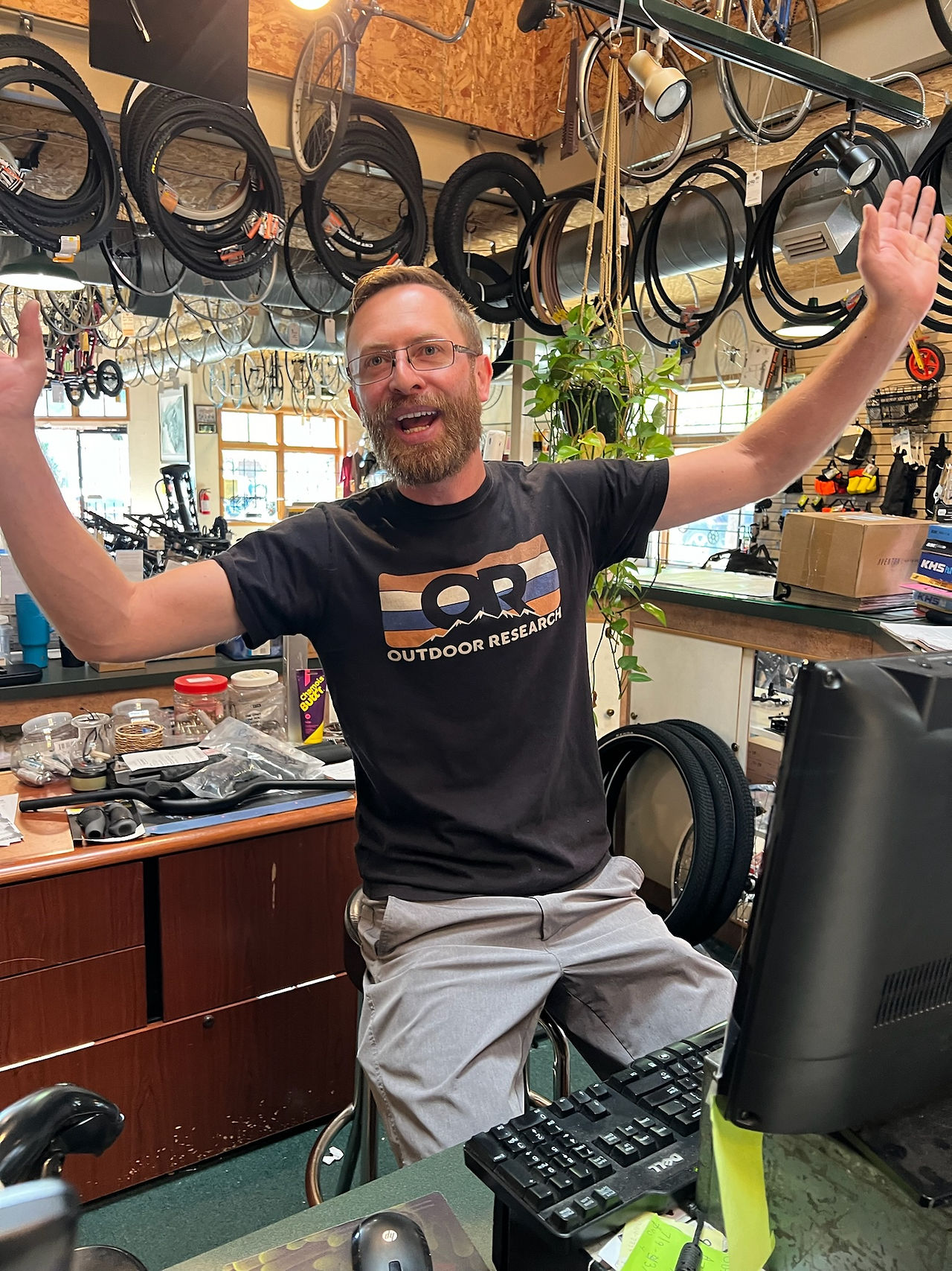 Bike Shop Employee with his arms up celebrating all the riders visiting for Bike Shop Appreciation Month.