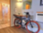 Bathroom Sink base has a bicycle below the counter with towels in the basket, with shower in the background with a bicycle printed shower curtain.
