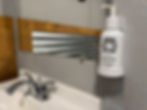 A refillable soap pump next to a sink with a mirror. The soap pump has the Buffalo Lodge Logo with the words purifying hand soap.
