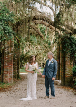 Wedding couple on the grounds of Greyfield Inn on Cumberland Island with a seasonal white, peach and pale blue bouquet.