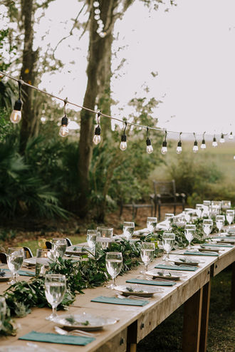Farmhouse table set for dinner with a lush, custom greenery garland with eucalyptus and candlelight glow.