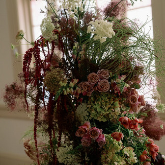 Close-up of textured floral arch with roses, hydrangea, and smokebush.