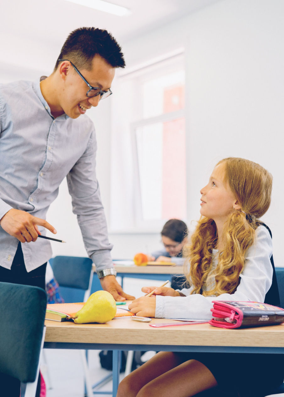 Teacher talking with student sitting at her desk