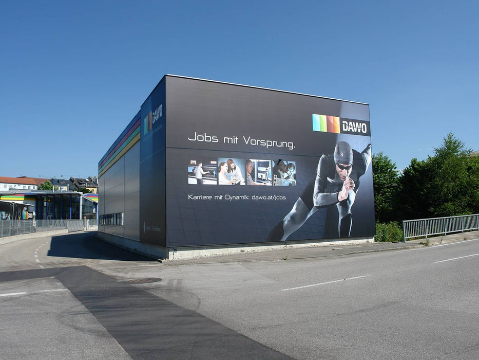 Großformatige Fassadenbespannung mit DAWO Werbemotiv an einer Gebäudefassade.