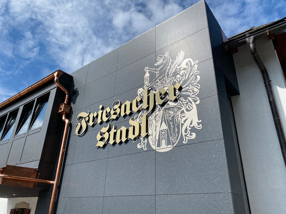 3D Buchstaben Friesacher Stadl mit Wappenmotiv auf einer grauen Fassade