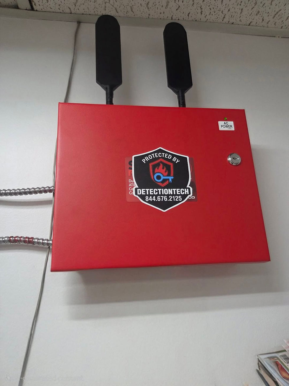 Red security panel with two black antennas on a wall, labeled "Protected by DetectionTech 844.676.2125," near an AC power sign.