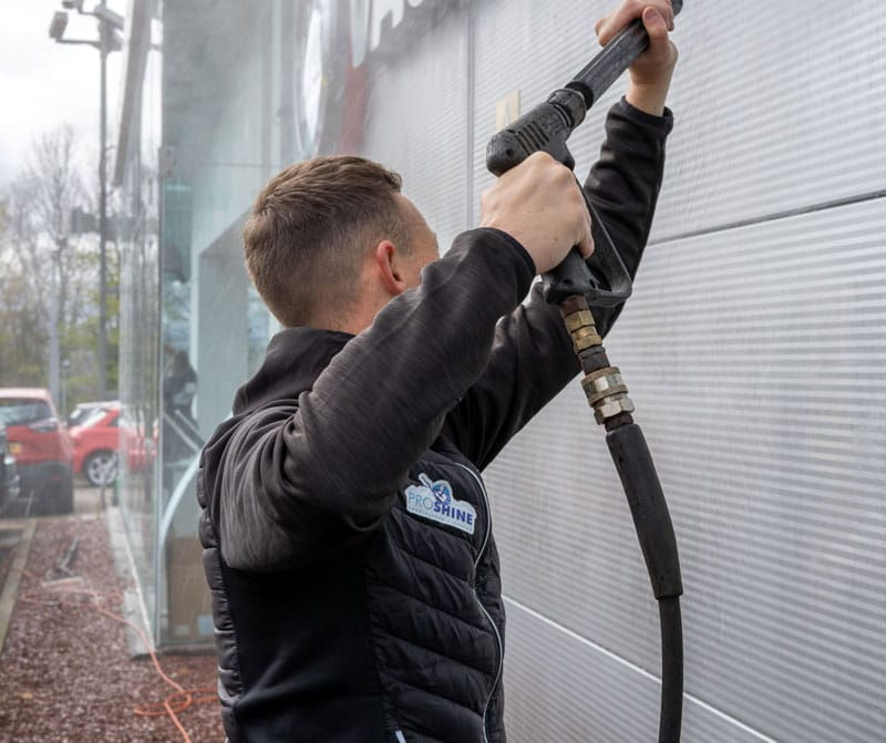 Young man jet washing commercial building.jpg