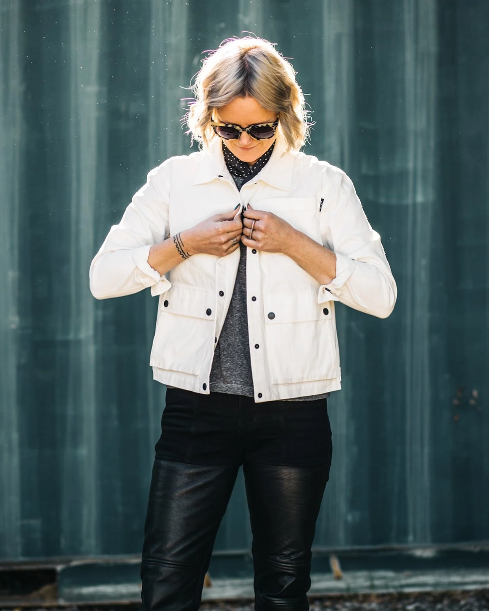 Thumbnail: Woman Buttoning Up an ATWYLD Pursuit Women's White Garage Jacket
