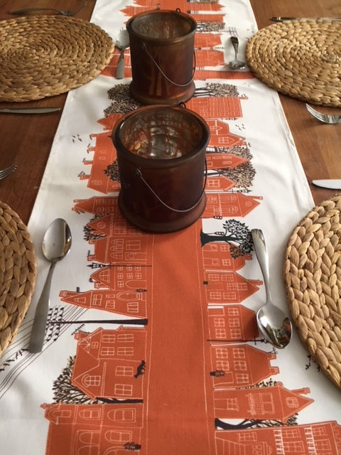 Miniatura: Burnt Orange Table Runner, depicting homes, trees and people walking down the road