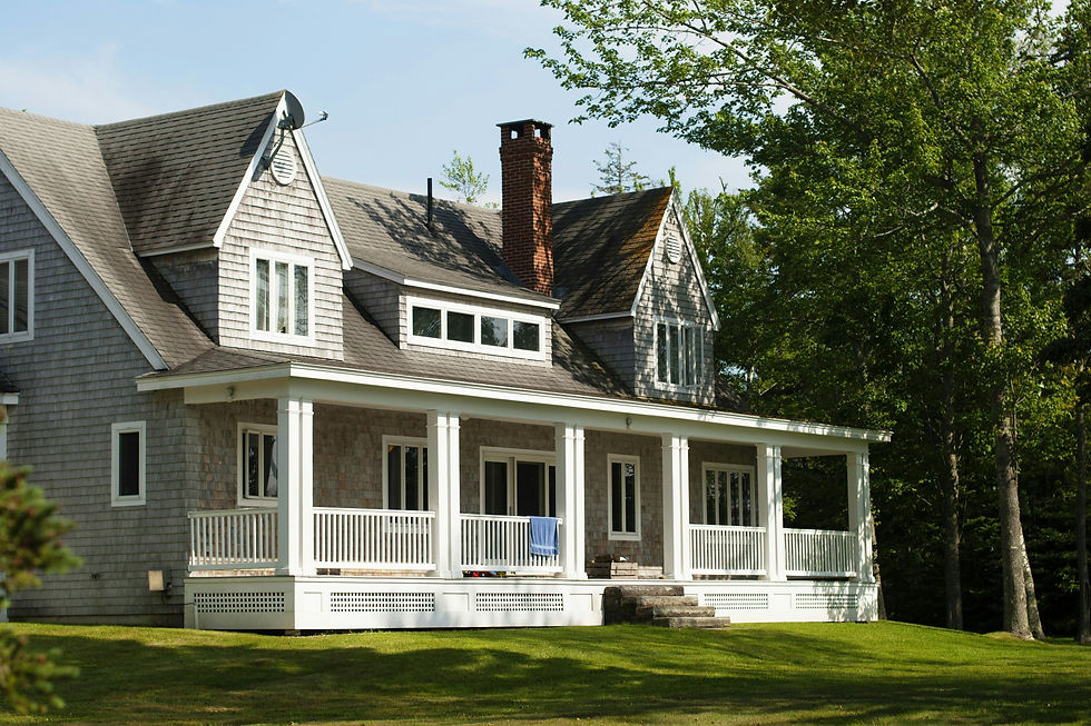 Large grey-shingled house with a spacious front porch and green lawn