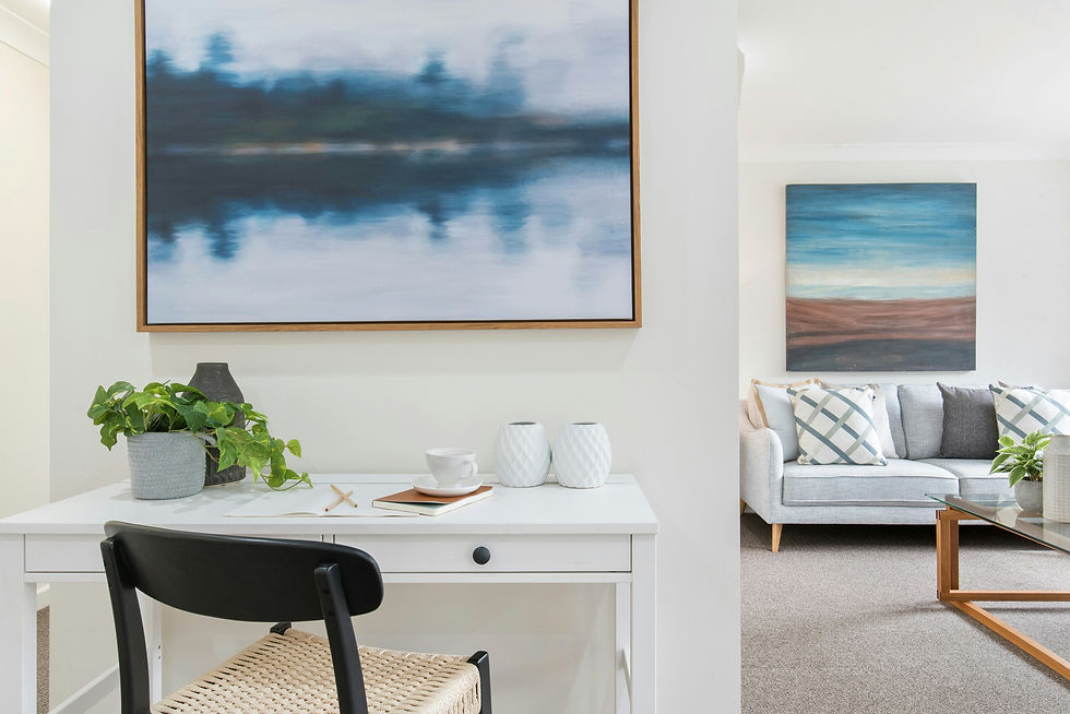 Bright and airy home office with abstract art and a cozy living room in the background