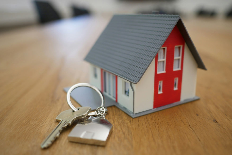 Small model house with red walls, key with fob on wooden surface