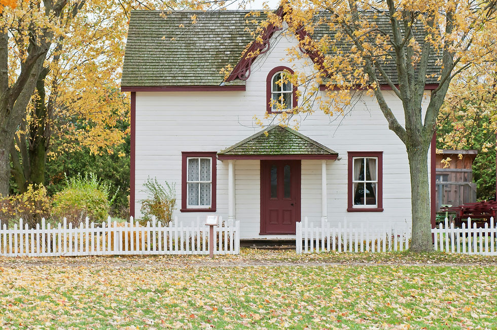 Quaint white country house with a red door and a white picket fence