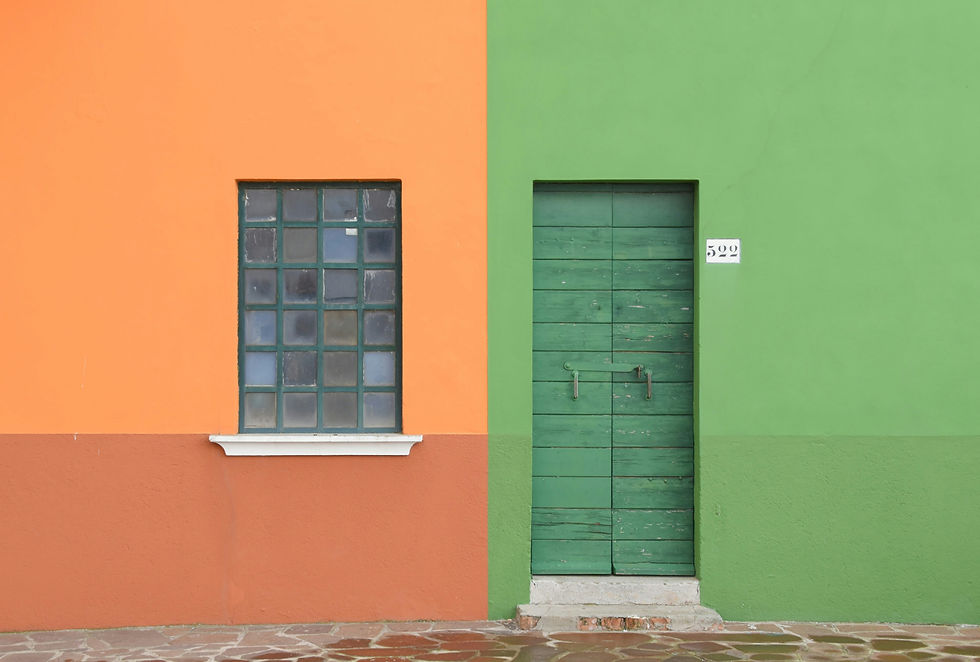 A vibrant orange and green facade with a square window and a rustic green door.