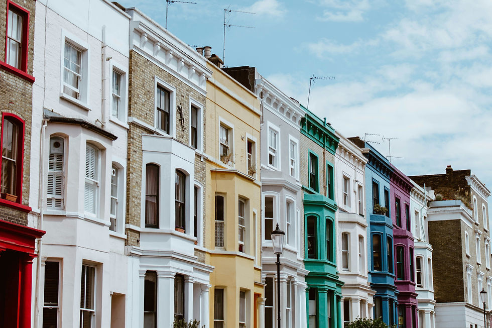 A row of colorful townhouses under a blue sky with fluffy clouds.
