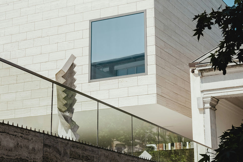 Modern building facade with a square window and zigzag sculpture reflected in the glass balustrade