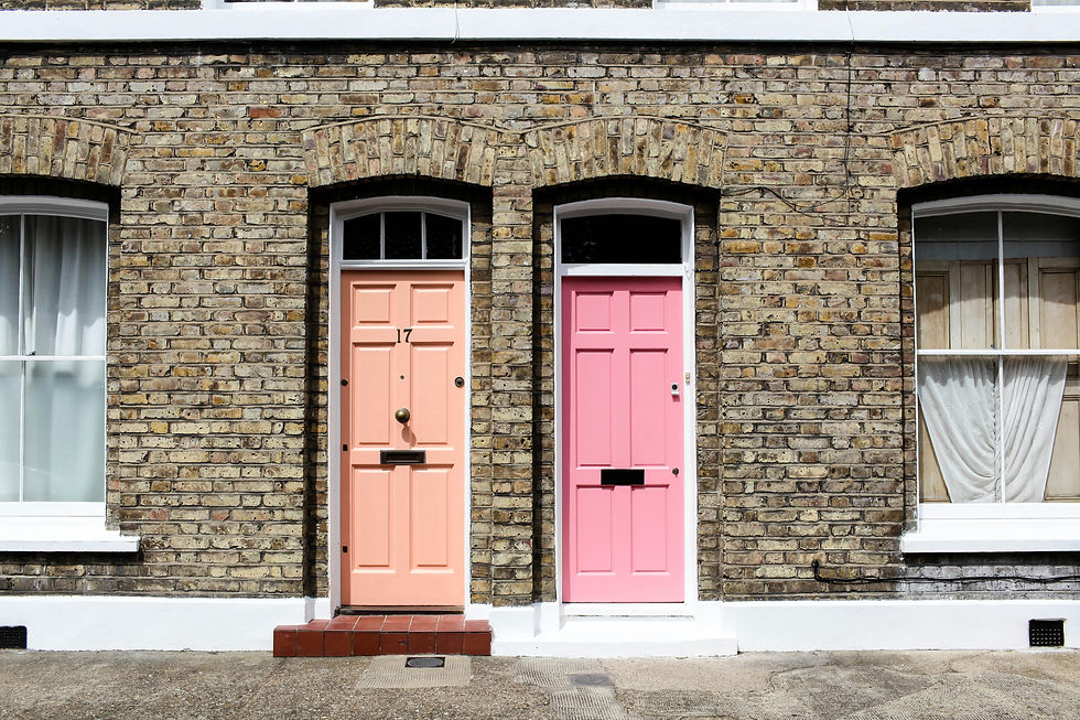 A row of traditional brick houses with pastel pink doors