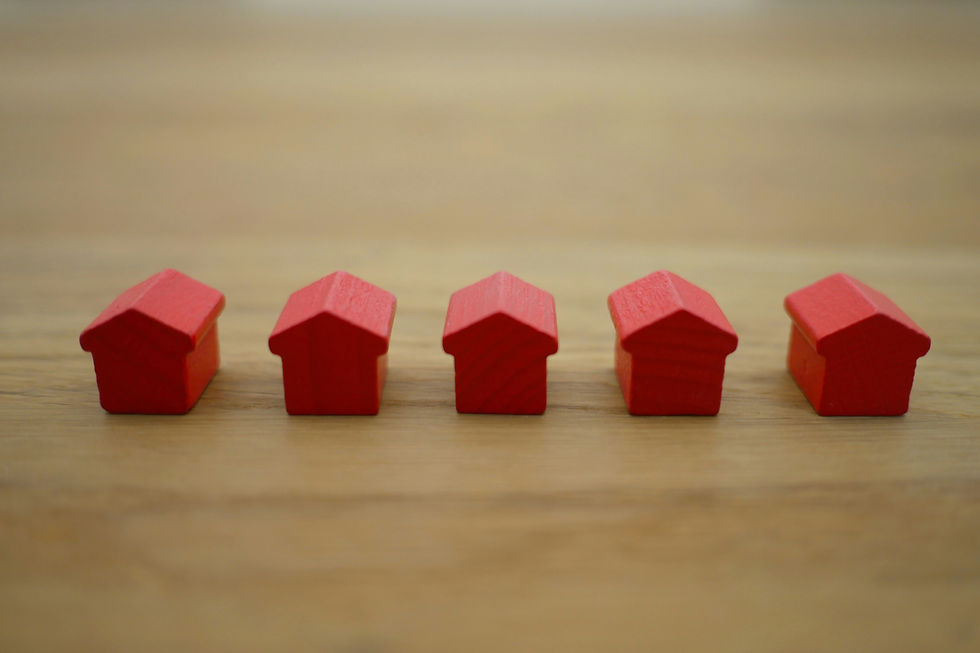 Five small red wooden house shapes in a row on a wooden surface