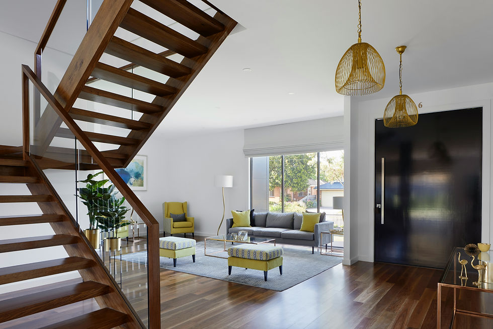 Open-plan living room with wooden staircase and gold pendant lights